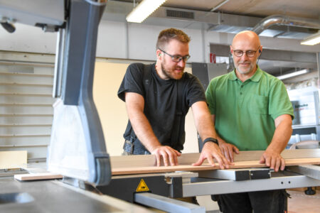 Zwei Männer bearbeiten Holz beim Tischlerei.