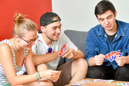 Drei Leute spielen Kartenspiel.